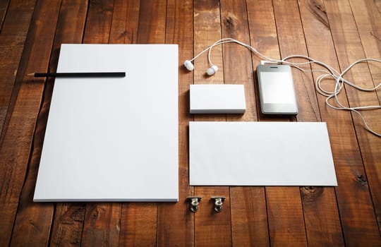 Blank stationery template on wood background. Blank letterhead, business cards, envelope, smartphone, headphones and pencil. Mock-up for design presentations and portfolios.