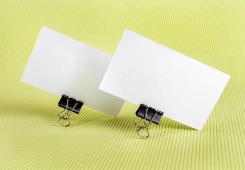 Photo of two blank business card with soft shadows on green background. Template for branding identity.