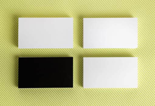 Blank black and white business cards on a green background. Template for branding identity. Top view.
