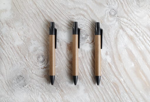 Three pens on a light wooden background. Template for design presentations and portfolios. Top view.