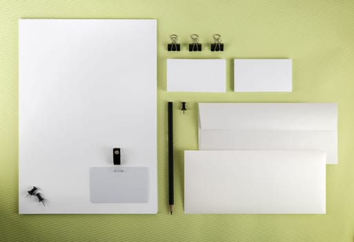 Blank branding identity set on a green background. Top view.