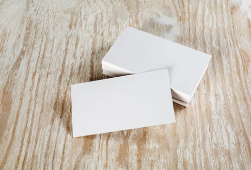 Blank business cards with soft shadows on light wooden background. Template for ID.