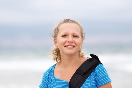 Smiling young blonde woman in a blue t-shirt outdoor. Closeup portrait. Shallow depth of field.  Focus on the model's face.