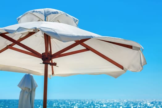 Big white parasol on a background of bright blue sky close-up. Beach umbrella.