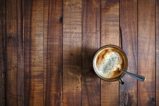 A cup of coffee on the background of the wooden table. Coffee on wooden background. Space for text. Top view.