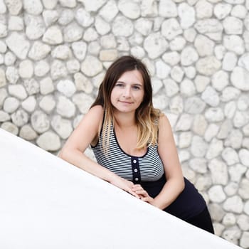 Pretty young woman with long hair posing on stained vintage background of stone wall. Shallow depth of field. Focus on the model's face. Space for text