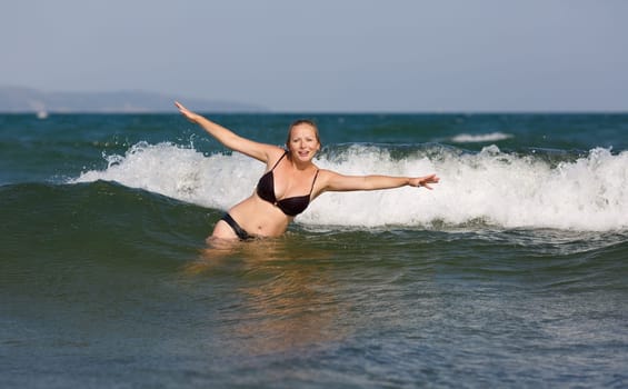 Smiling beautiful woman on the background of sea wave on a bright sunny day.