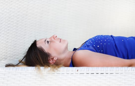 Close-up of a beautiful young woman in a blue shirt relaxes lying and looking up. Shallow depth of field. Selective focus on the model's face.