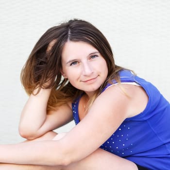 Portrait of pretty young woman with long hair in blue shirt looking at the camera. Selective focus on the model's face.