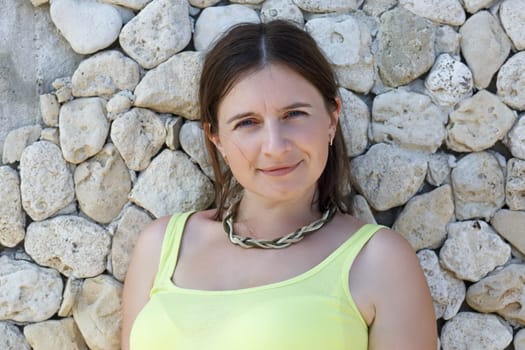 Portrait of pretty young woman in green t-shirt on stone wall background closeup.
