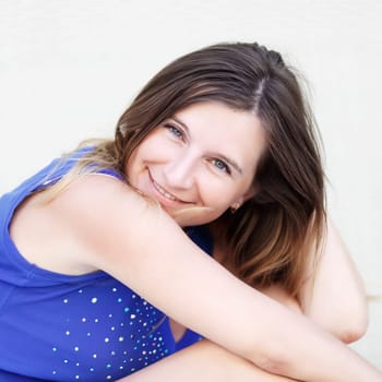 Pretty young woman in a blue shirt with long hair looking at the camera and smiling. Closeup portrait. Shallow depth of field.