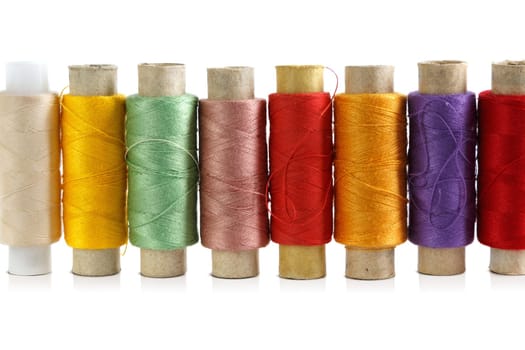 Several spools of brightly colored threads on a white background