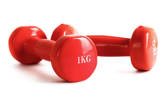 Red dumbbell on a white background. Shallow depth of field.