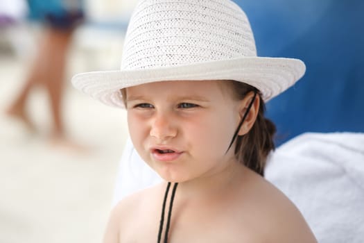 Portrait of a baby in a white hat on a bright sunny day closeup. Shallow depth of field. Focus on the model's face.