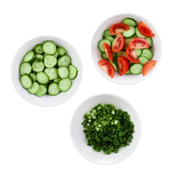 Fresh tomatoes, cucumbers and green onions chopped in salad. Three plates of salad isolated on a white background.