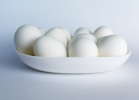 White eggs on a white plate on a light background