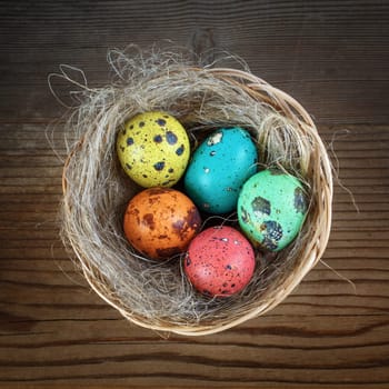 Photo of Easter eggs in the nest on wooden background. Top view.