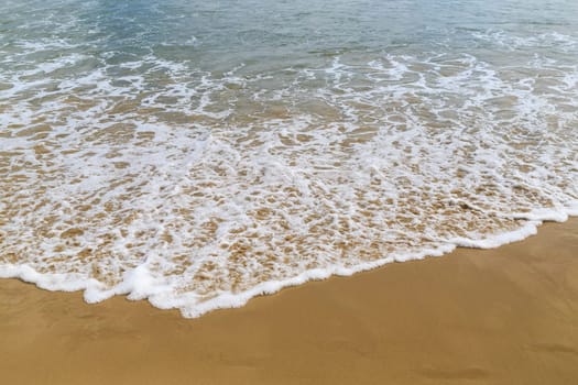 Sea surf on a sandy beach closeup