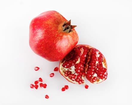 Ripe pomegranate and its half with reflection on a light background. Studio shot. Top view.