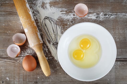 Cooking still life with eggs, eggshells, flour and rolling pin.
