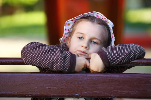 Close-up outdoor portrait of a serious little girl. Pensive child. Shallow depth of field. Selective focus.