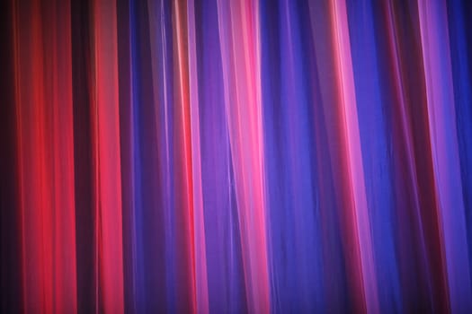 Purple theater curtain. Abstract purple background. Closeup of a theater curtain. Curtains theater lit by bright light of spotlights.