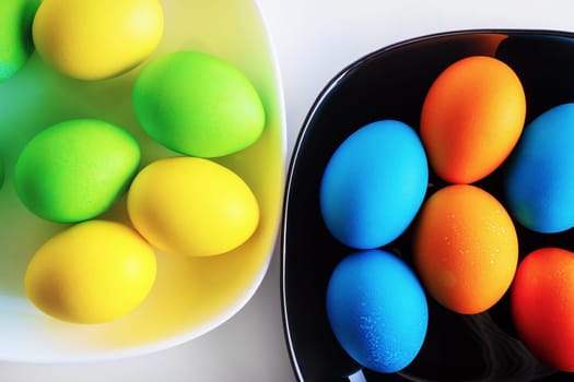 Bright colored Easter eggs in a black and white dishes.