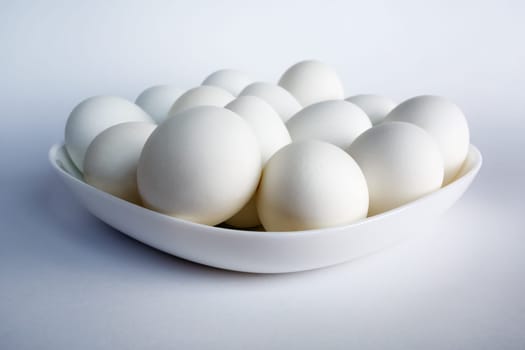 Photo of white eggs on a white square dish on a light background.
