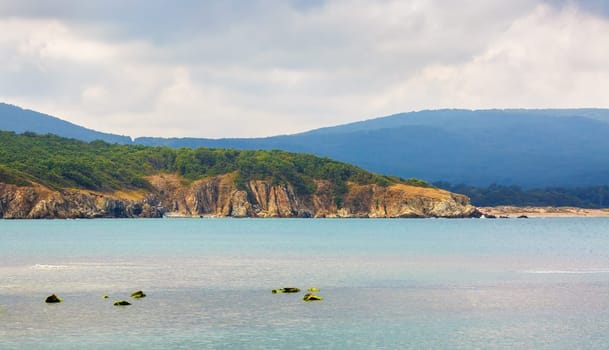 Beautiful seascape. Rocky shore wooded mountains and the sea.