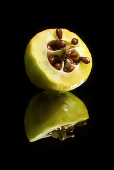 Quince cut in half with seeds on a black background with reflection. Vertical shot.