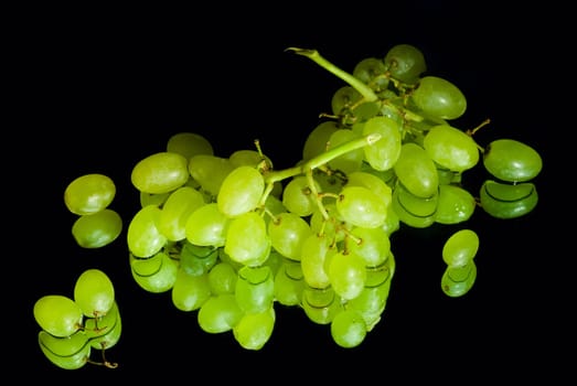 Bunch of fresh green grapes with reflection on black background.