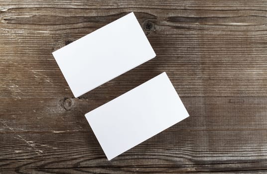 Two stacks of blank business cards on a dark wooden background. Template for branding identity. Top view.