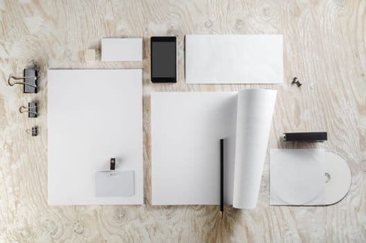Photo of blank stationery set on light wooden background. Template for design presentations and portfolios.