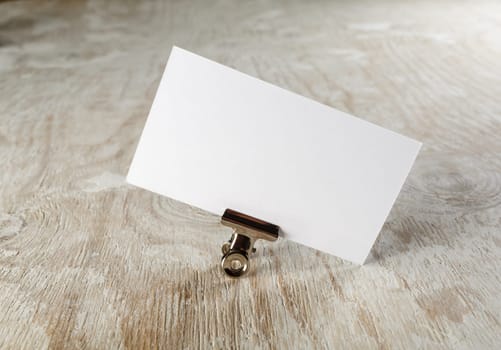 Photo of blank business card with soft shadow on light wooden background. Mock-up for branding identity.