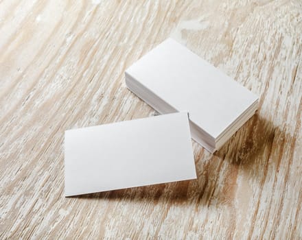 Photo of blank business cards with soft shadows on light wooden background. For design presentations and portfolios.