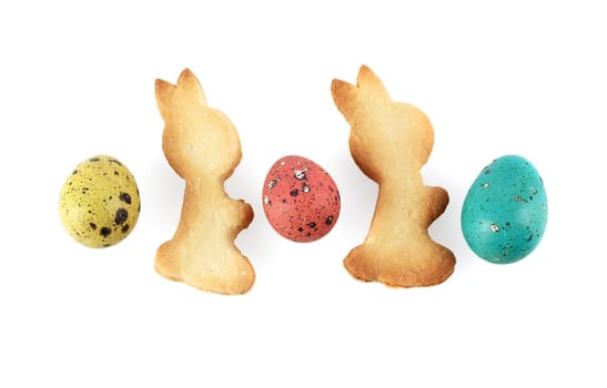 Multicolored painted quail eggs and biscuits in the shape of rabbits on a white background. Isolated with clipping path.