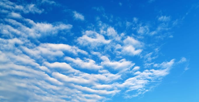 Blue sky with white cirrus clouds on a bright sunny summer day. Panoramic shot.