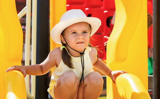 Portrait of a baby in a white hat and a yellow t-shirt on the playground on a sunny day. Shallow depth of field. Focus on model.