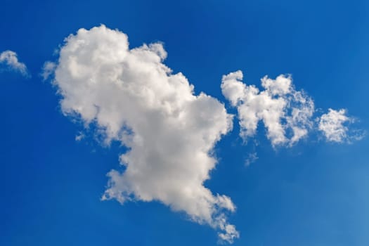 White cumulus clouds against a bright blue sky on a sunny day.