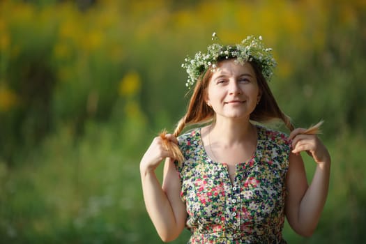 Smiling girl with a wreath keeps his hair. Sunset light. Space for text. Shallow depth of field. Focus on eyes.