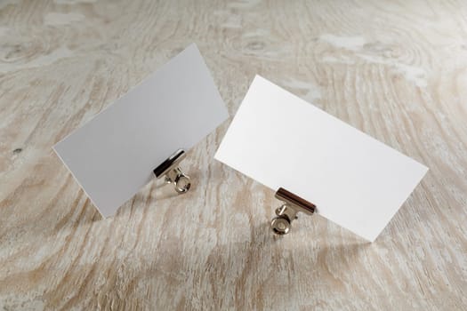 Photo of blank business cards with soft shadow on light wooden background. Mock-up for branding identity.