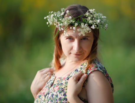 Portrait of a pretty young woman with a wreath on his head in the sunset light. Sunset light. Shallow depth of field. Focus on eyes.
