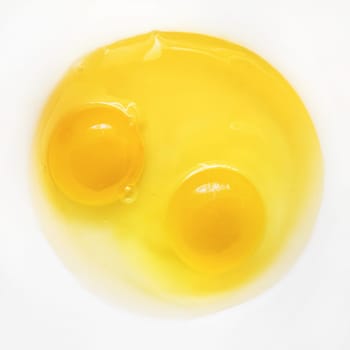 Raw eggs on white plate. Two broken eggs. Yolk and white.