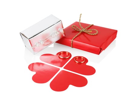 Gift box with red paper hearts and wedding rings on a white background. Isolated with clipping path.