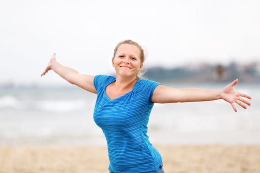 Beautiful young woman enjoying freedom. Free happy girl posing arms outstretched to the side and looking at the camera.