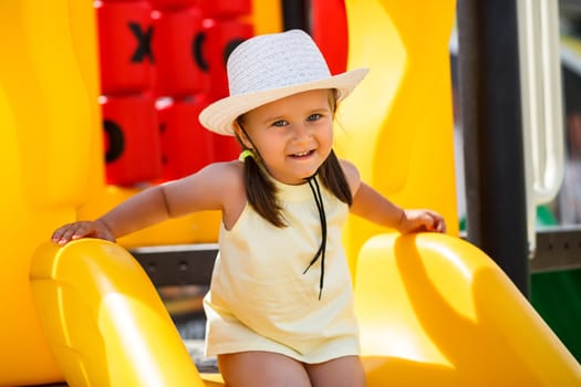 Child in a white hat and a yellow T-shirt playing in the playground. Shallow depth of field. Focus on the model's face.