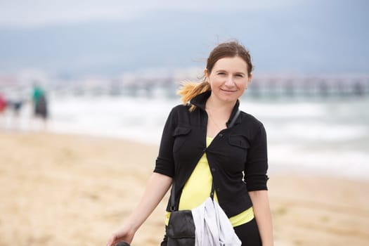 Smiling woman in a black blouse with a blurred background beach and sea.  Shallow depth of field. Focus on model.