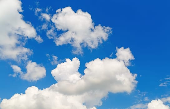 Blue sky background with white cumulus clouds on a sunny day.