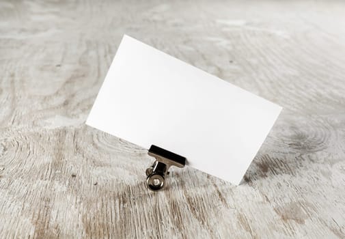 Photo of blank business card with soft shadow on light wooden background. Mock-up for branding identity. Blank template for your design.
