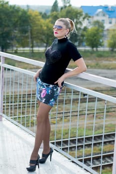 the sexy beautiful woman on the bridge in a miniskirt, against railway tracks, railway roads, a subject beautiful women in different places